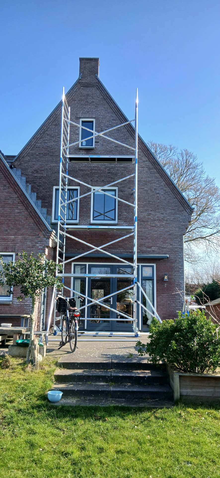 Bakstenen woning met steiger tijdens buitenschilderwerk