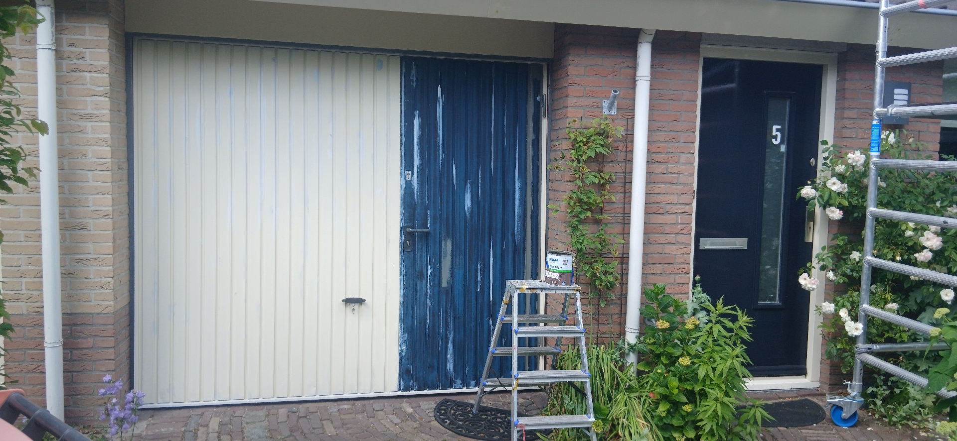 Schuren van een blauwe houten deur als voorbereiding op schilderwerk