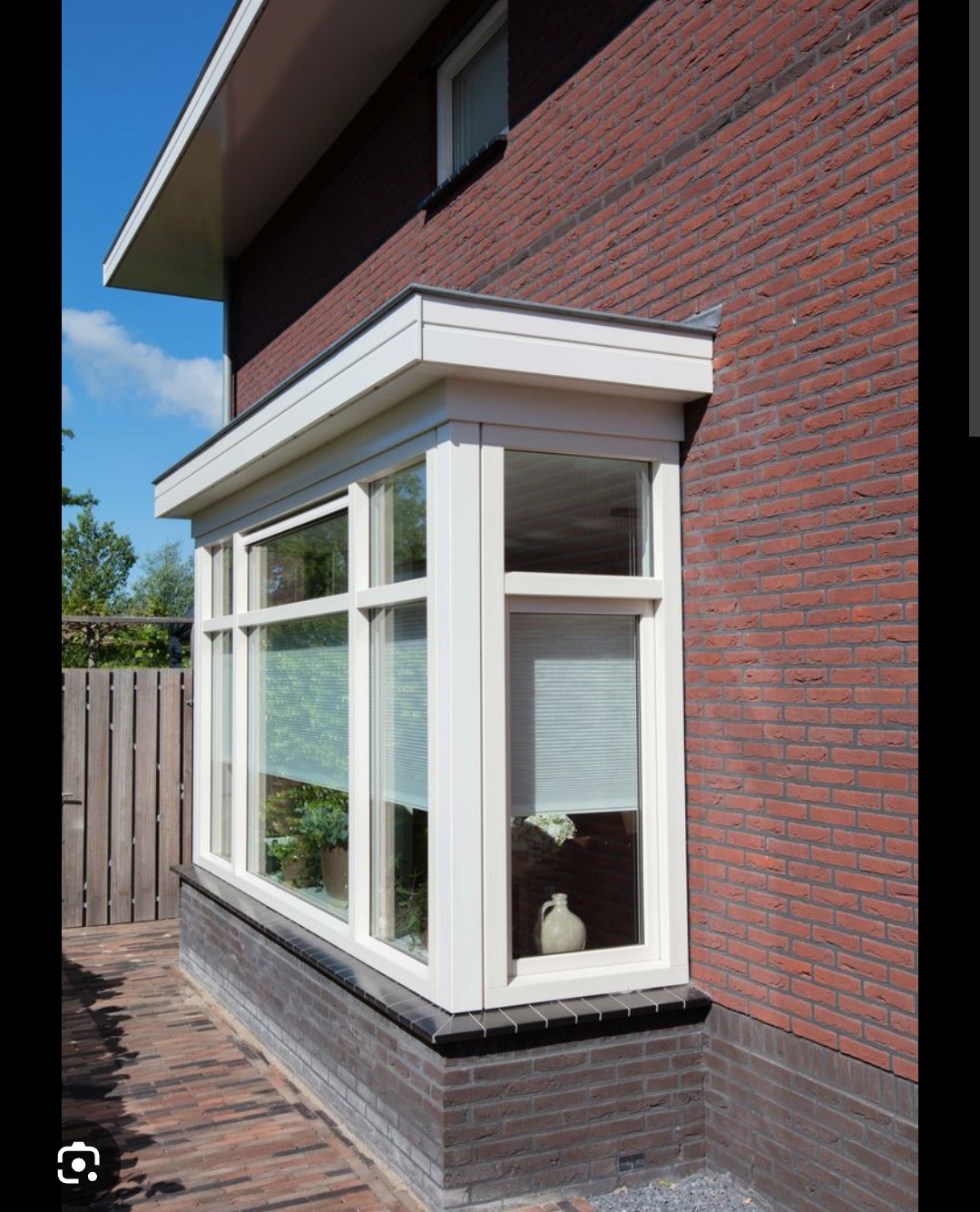 Witte houten erker aan bakstenen woning in Bakkum na volledige schilderbeurt