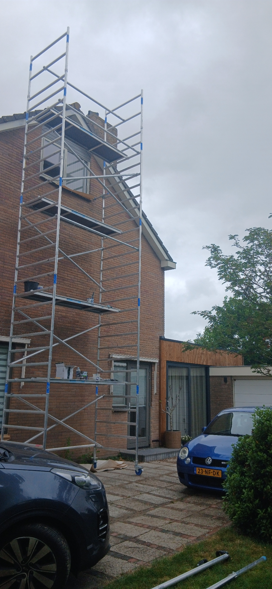 Schilder uit Limmen aan het buitenschilderwerk vanaf een steiger bij een woning aan de Westerweg in Limmen